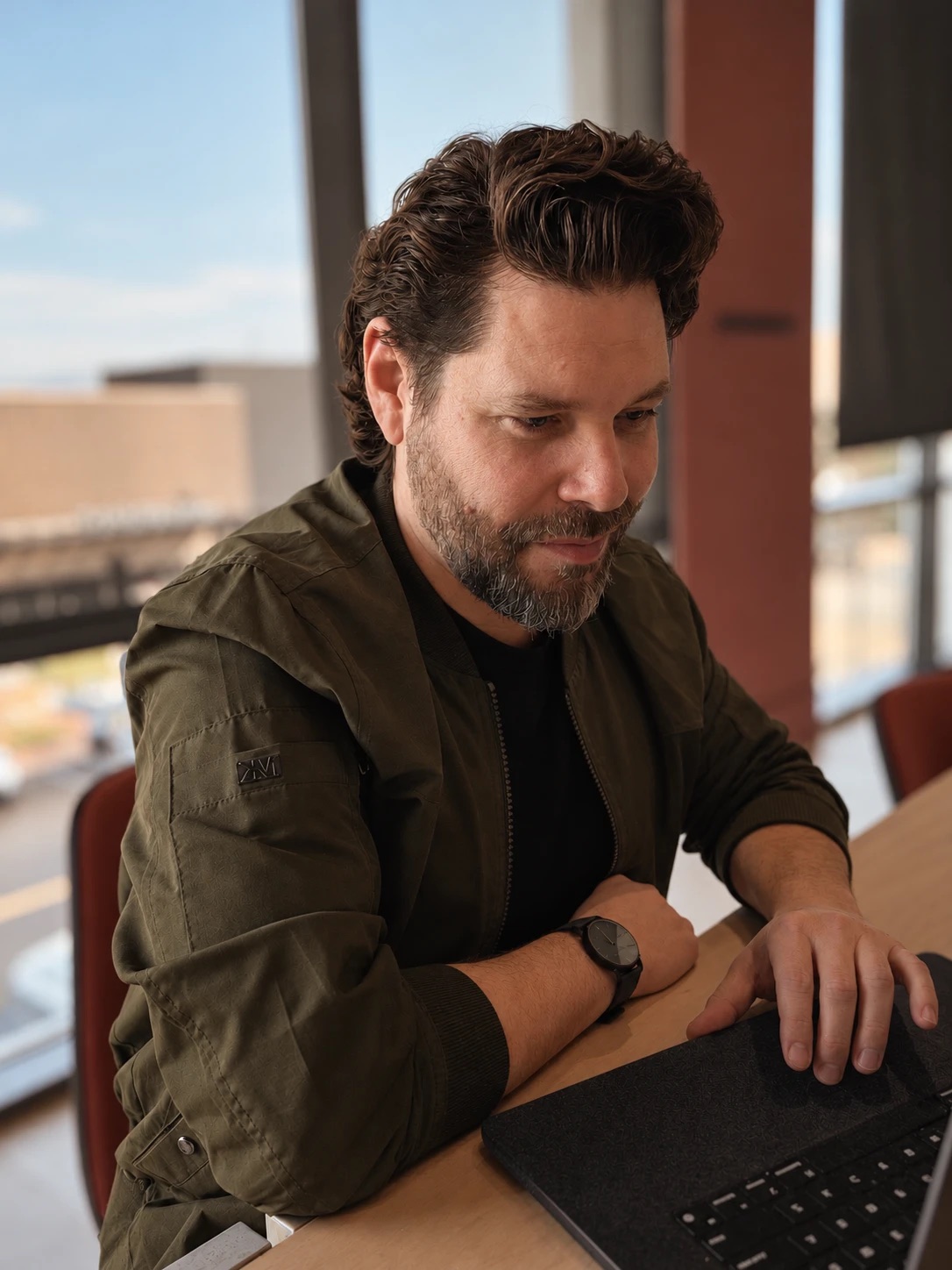 Jonathan Greye working on a laptop by a sunlit window