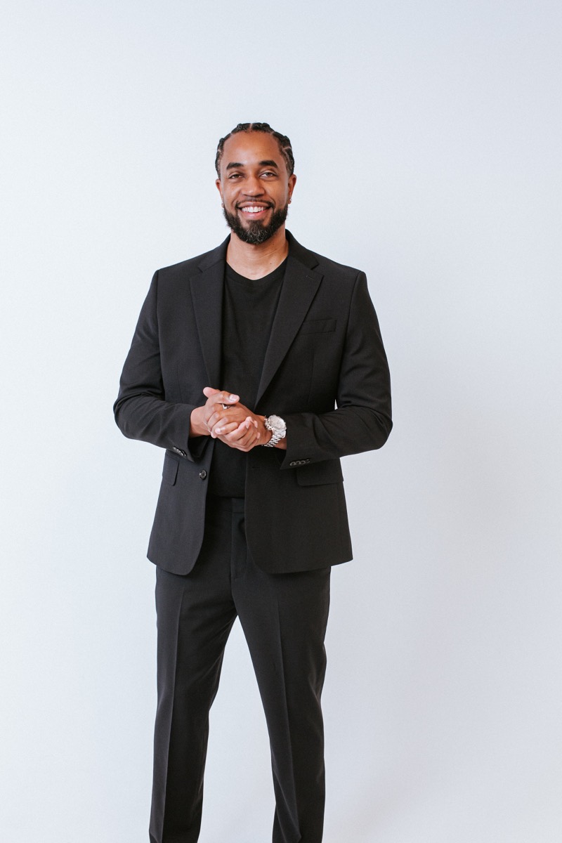 Cliff Worley standing in a black suit, hands clasped