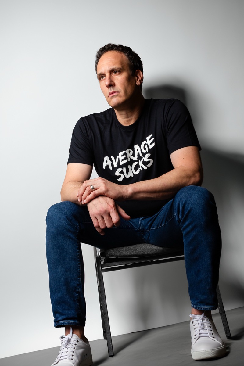 Michael Bernoff seated in an Average Sucks t-shirt