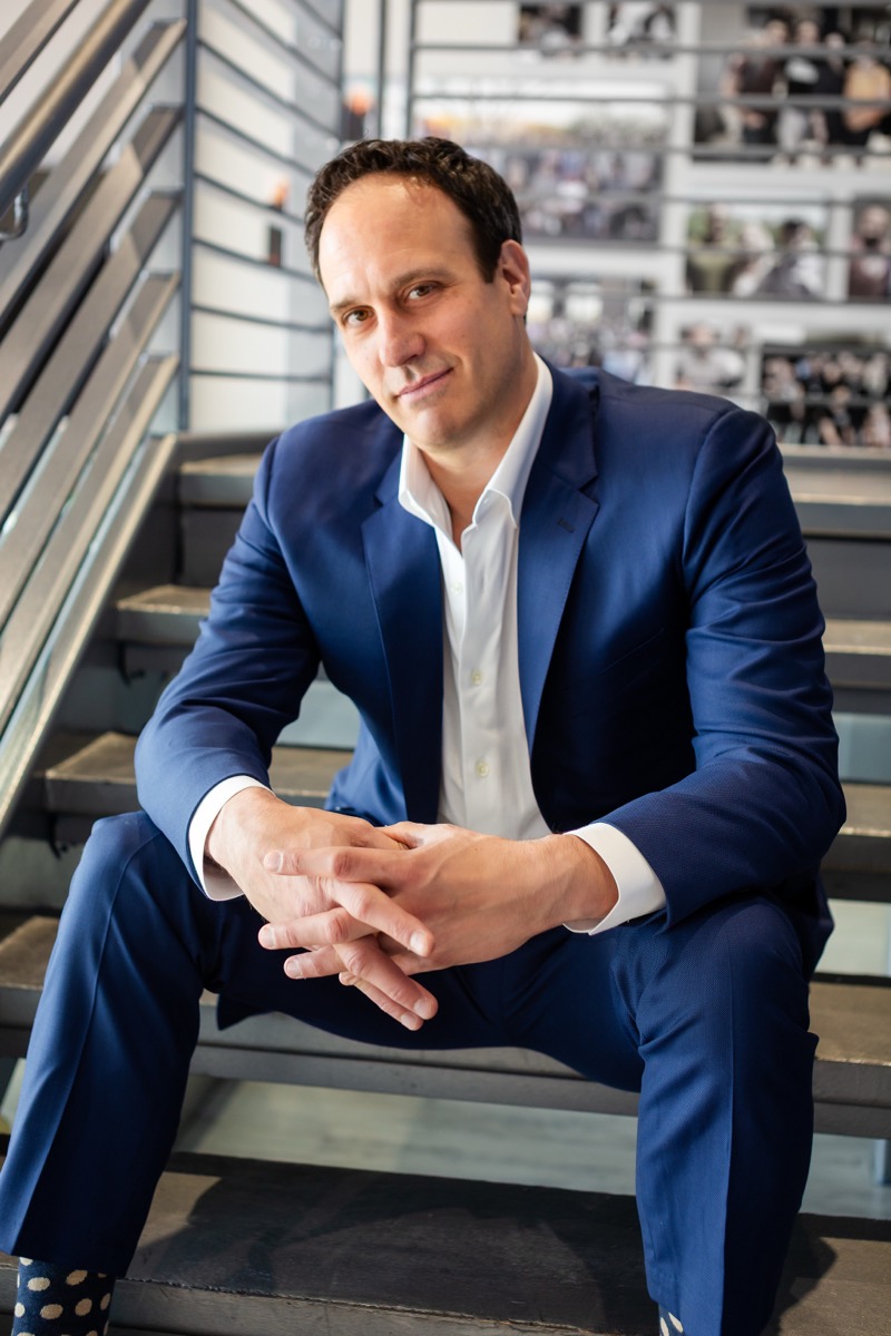 Michael Bernoff seated on steps in a blue suit