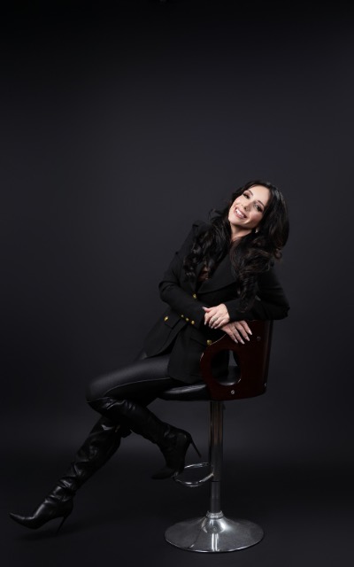 Sara Wolfe seated on a stool against a dark background