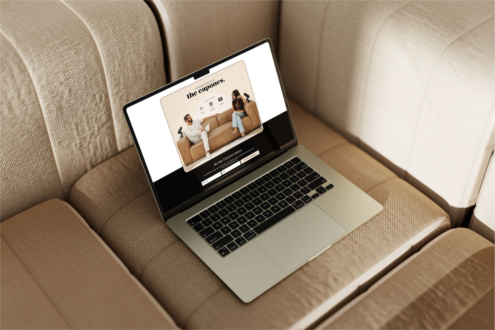 The Capones website on a laptop resting on a beige sofa