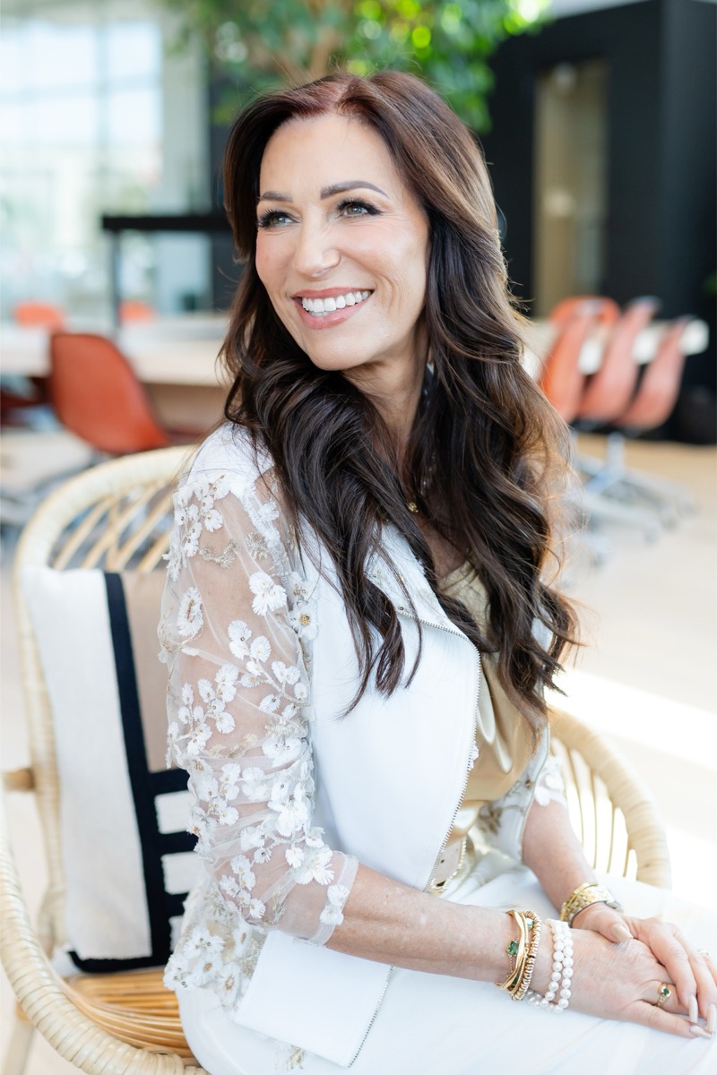Tina Schaaf smiling in a white lace jacket in a bright office