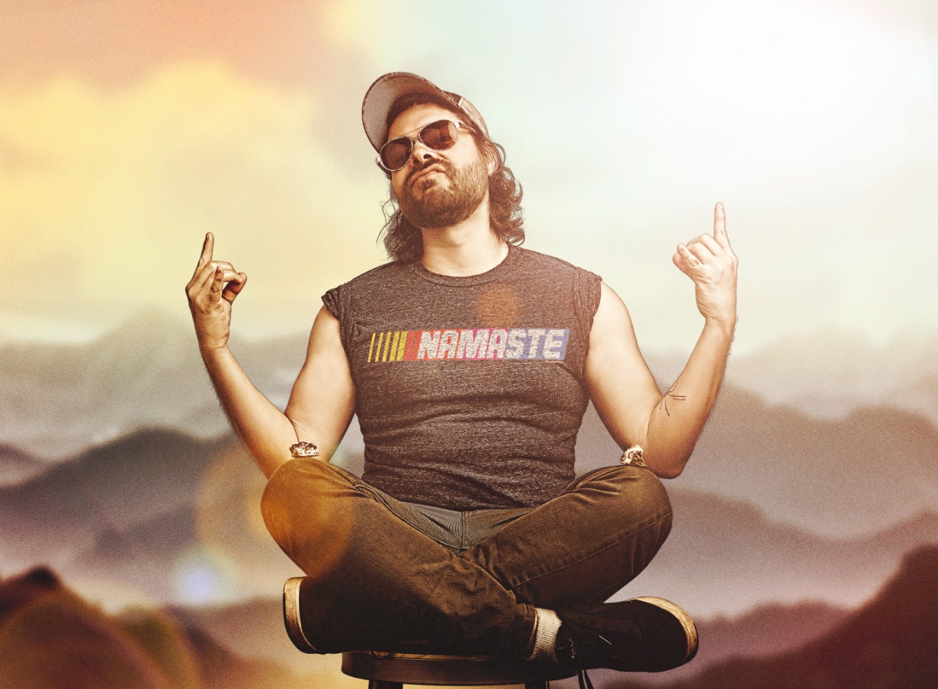 Ben meditating on a stool in a Namaste shirt styled like a racing logo